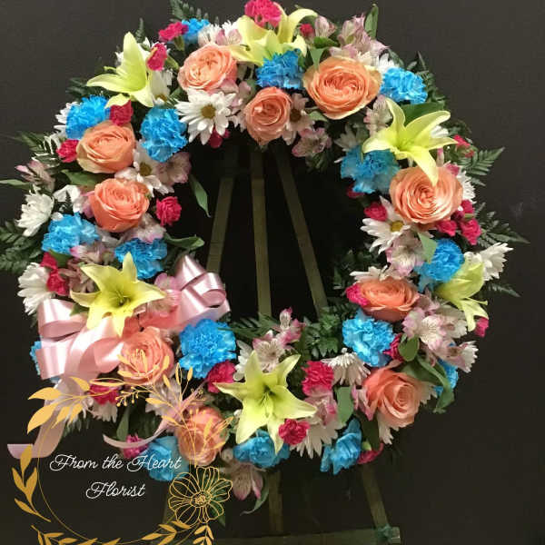 Colorful floral wreath with roses, lilies, and daisies on a stand