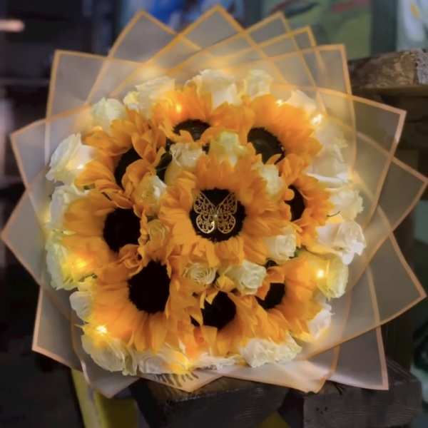 Bouquet of orange sunflowers and white roses wrapped in translucent paper