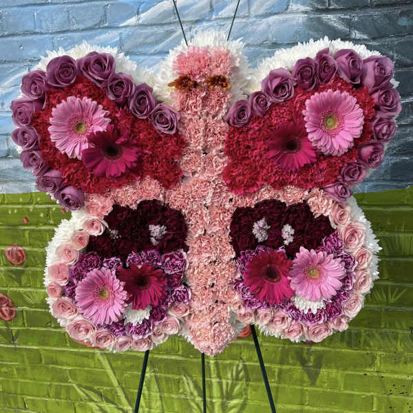 Butterfly-shaped floral arrangement in pink, purple, and white on an easel