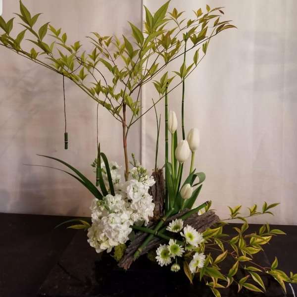 White floral arrangement with tulips and daisies in a low container