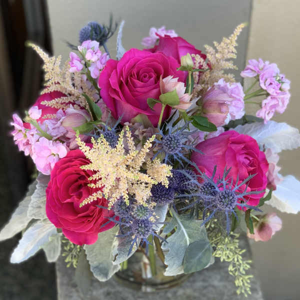Bouquet of hot pink roses with lavender accents in a glass vase