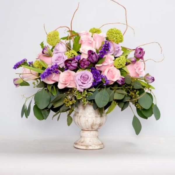 Pink and lavender roses in a white pedestal vase