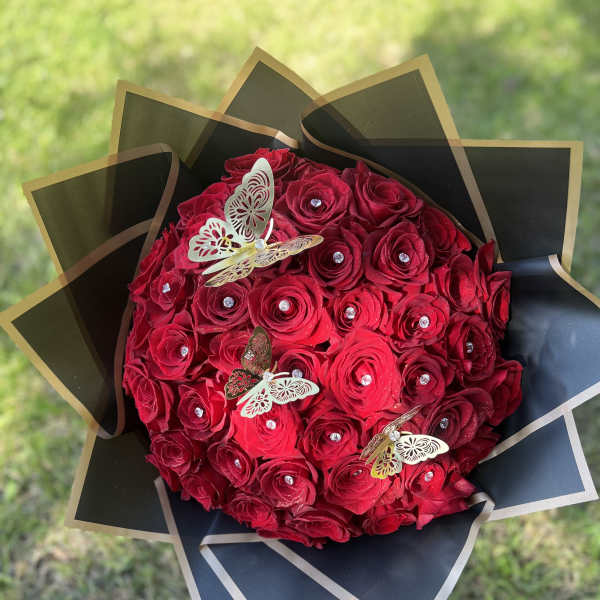 Bouquet of red roses wrapped in black paper with butterfly accents