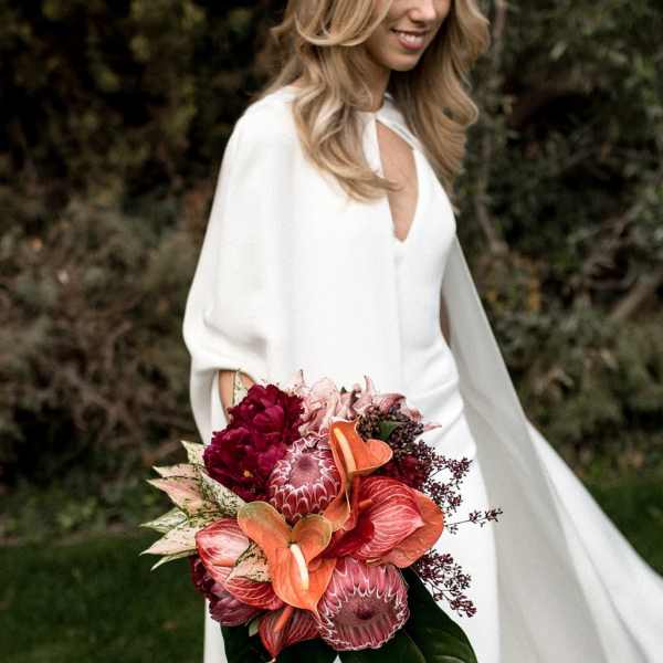 Bride holding a bouquet of red and orange tropical flowers