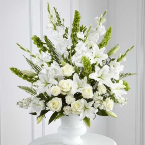 White floral arrangement in a white vase with green accents