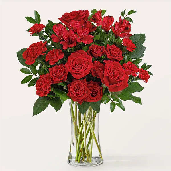 Red roses and carnations in a clear glass vase