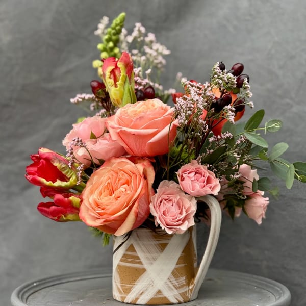 Bouquet of pink and peach roses in a striped ceramic mug