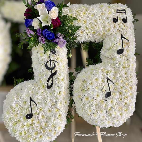 Standing floral tribute shaped like musical notes in white flowers with purple and blue accents