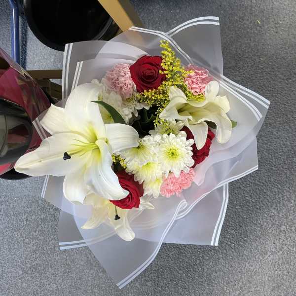 Bouquet of white lilies, red roses, pink carnations, and white daisies