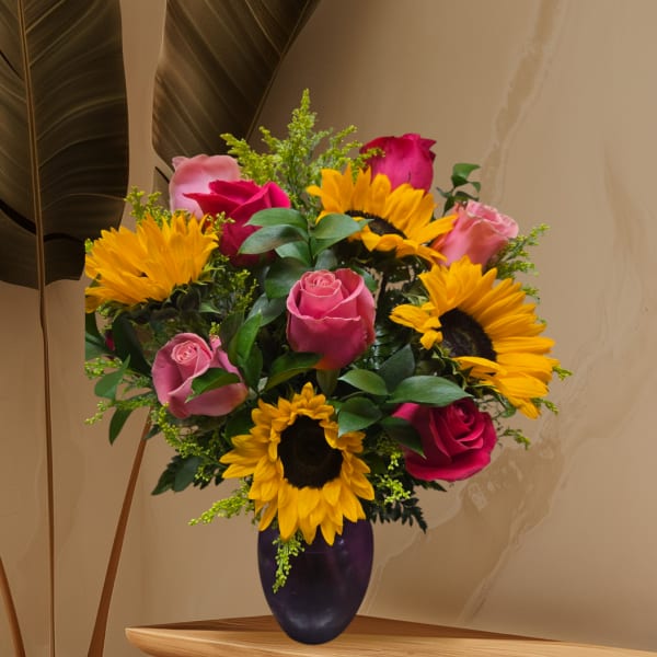 Bouquet of pink roses and sunflowers in a dark vase