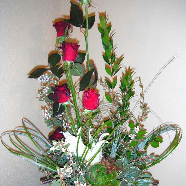Tall arrangement of red roses and succulents in a black pot