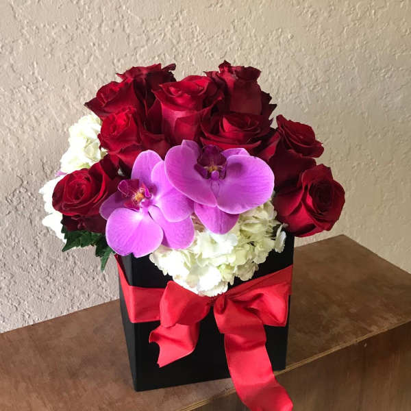 Red roses and purple orchids in a black box with a red ribbon