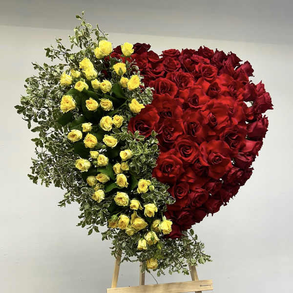 Heart-shaped arrangement of red and yellow roses on an easel