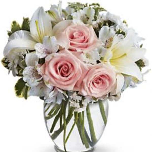 Pink roses and white lilies arranged in a clear glass vase