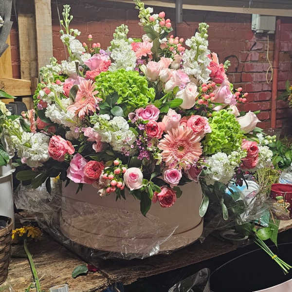 Large pink and white floral arrangement in a round box
