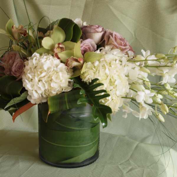 White and blush floral arrangement in a green vase
