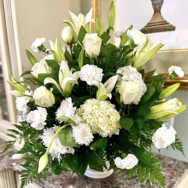 White floral arrangement with lilies, roses, hydrangea, and carnations