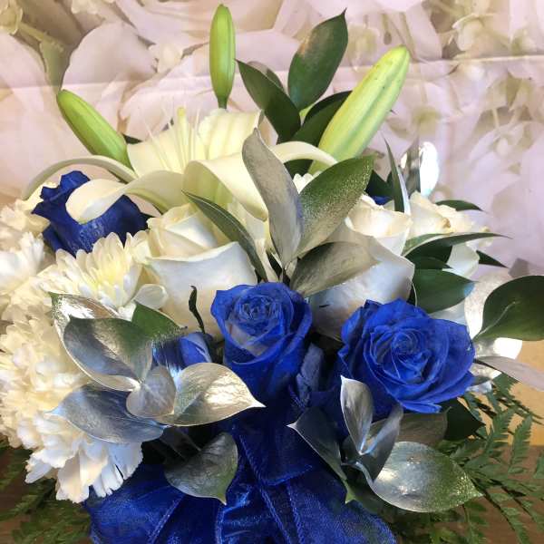 Blue and white floral arrangement with roses, lilies, and carnations in a vase