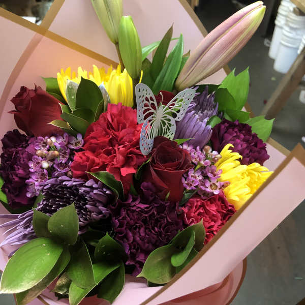 Colorful bouquet with roses, lilies, chrysanthemums, and carnations in pink wrap