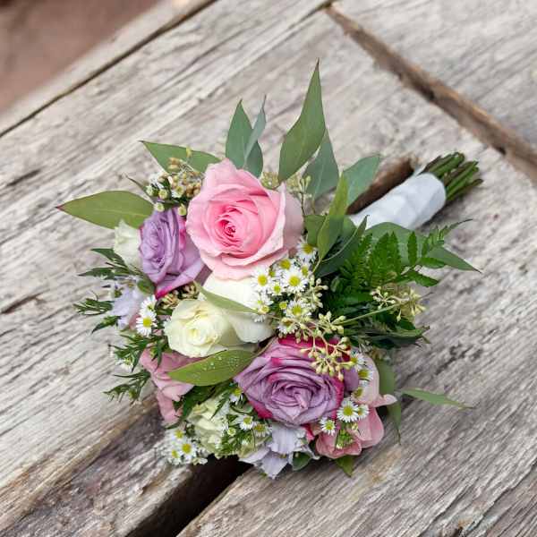 Hand-tied bouquet of pink, lavender, and white roses with small white daisies