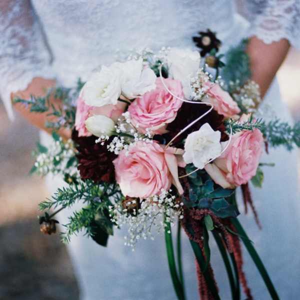 Bride holding a bouquet of pink and white roses with greenery