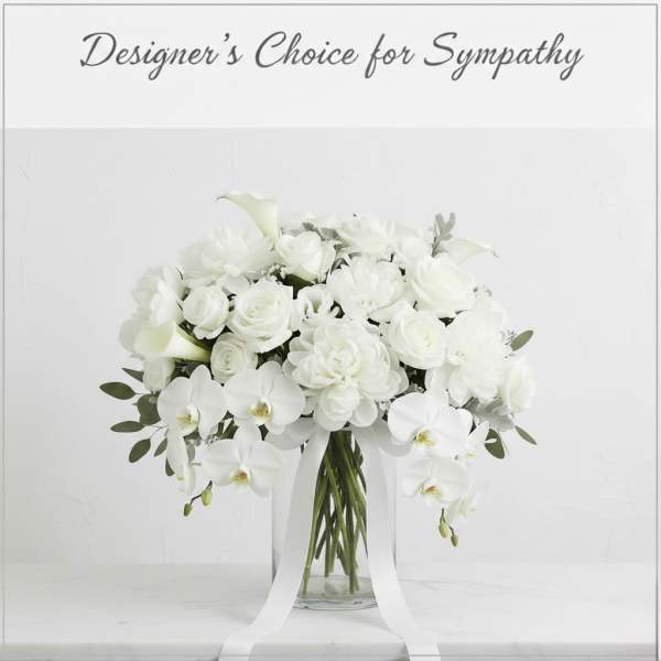 White floral arrangement in a clear glass vase with trailing ribbon