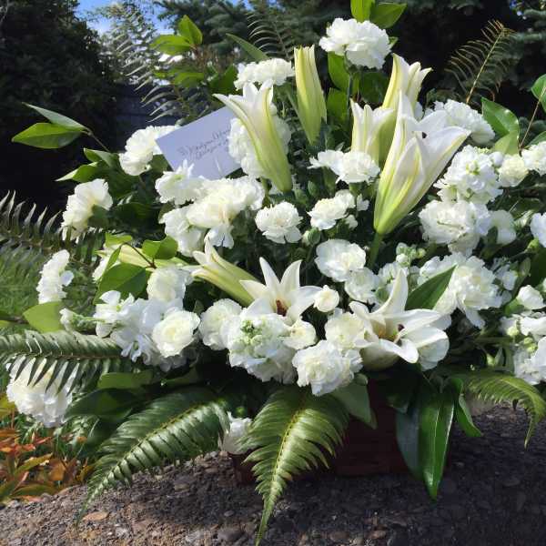 Large white floral arrangement with lilies and carnations in a basket