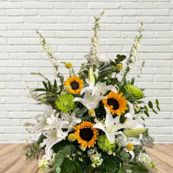 Arrangement of white lilies and sunflowers with green accents