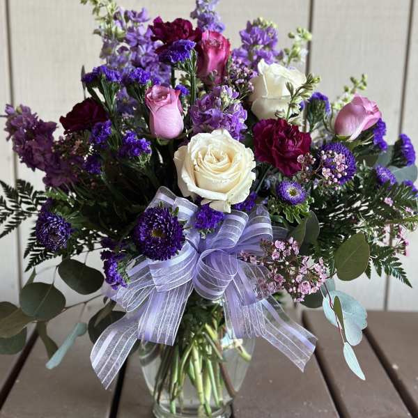 Bouquet of purple and pink flowers with white roses in a glass vase