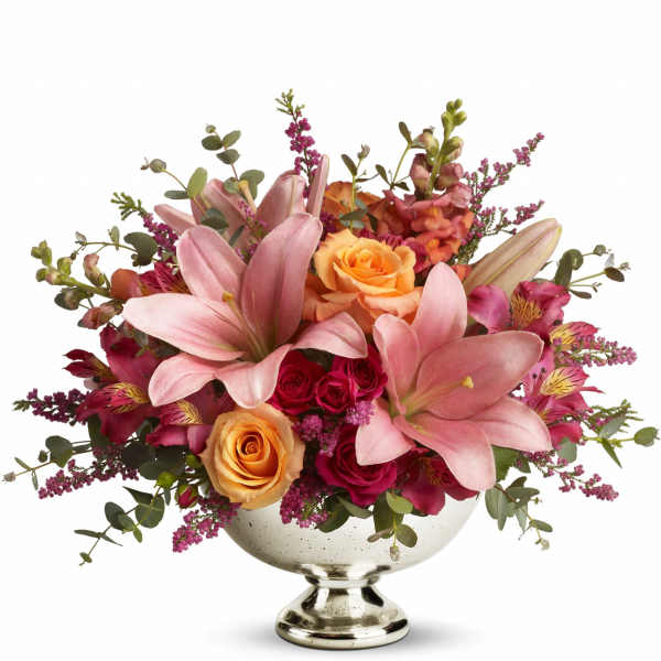 Pink lilies and roses arranged in a silver pedestal vase