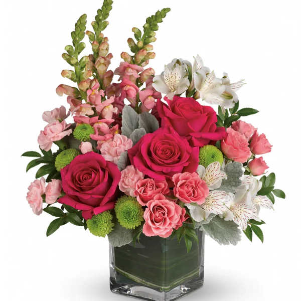 Pink roses and mixed blooms arranged in a clear square vase