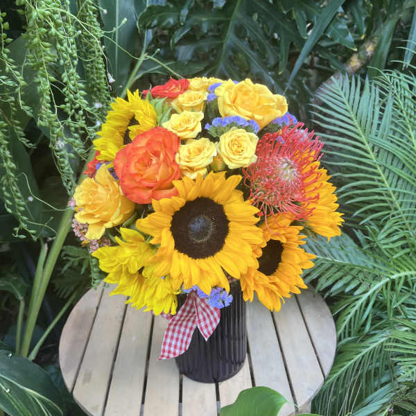 Bouquet of sunflowers and yellow-orange roses in a dark vase
