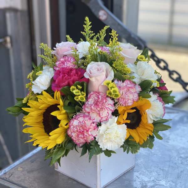 Mixed bouquet with sunflowers, pink roses, and carnations in a white box