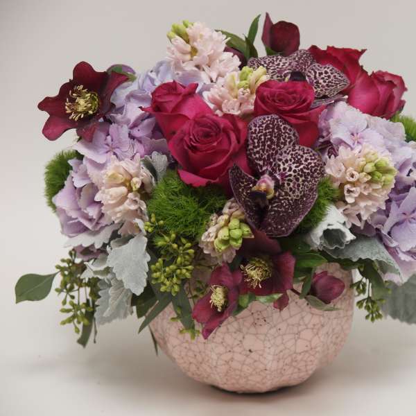 Pink and purple floral arrangement in a cracked ceramic bowl