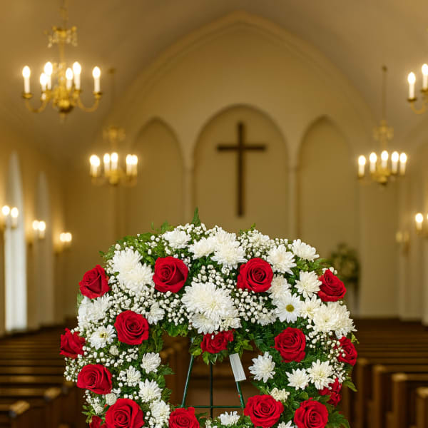 Heart-shaped floral wreath of red roses and white flowers on an easel