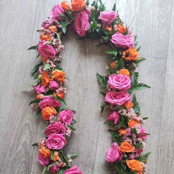 Floral wreath of pink and orange roses on a wood floor