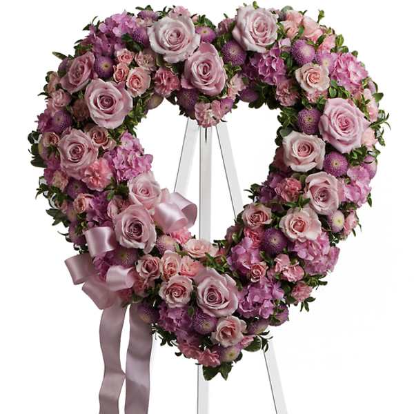 Heart-shaped pink floral wreath on a white easel with ribbon
