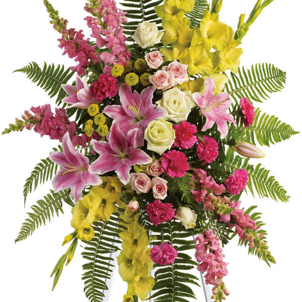 Standing floral spray with pink lilies, roses, and yellow gladiolus on an easel