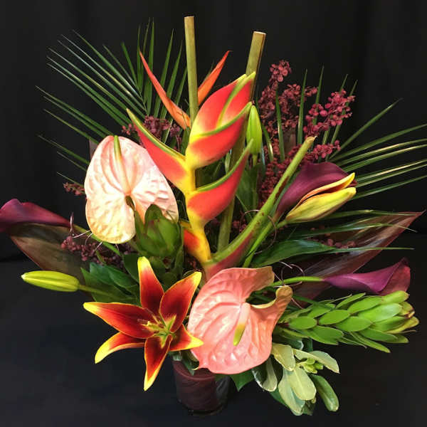 Tropical bouquet with anthuriums, lilies, and palm fronds in a vase