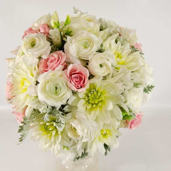 Round bouquet of white and pink flowers in a clear vase
