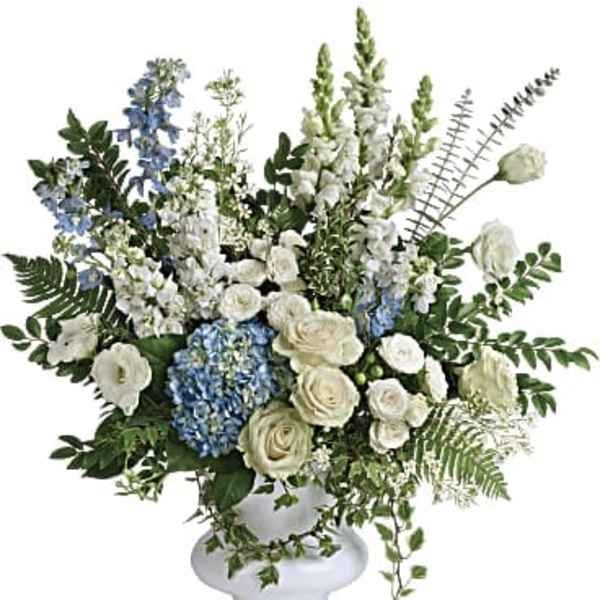 White and blue floral arrangement in a white pedestal vase