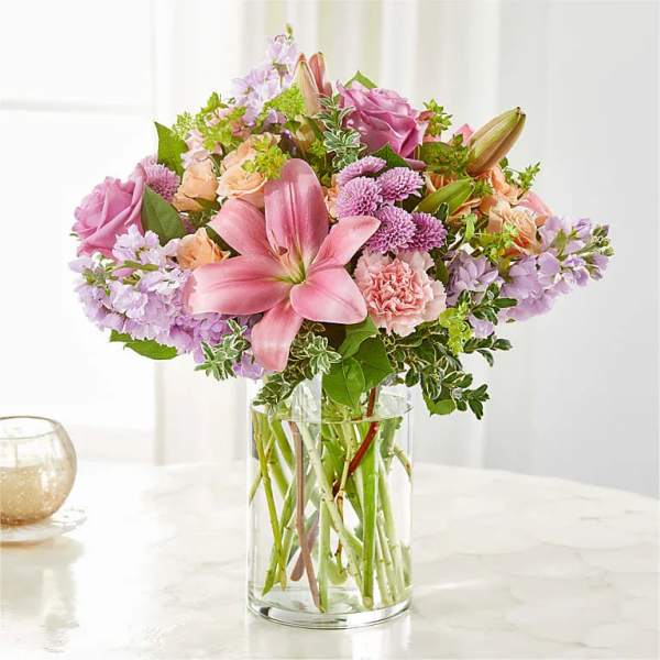 Pink lilies and mixed pastel flowers in a clear glass vase