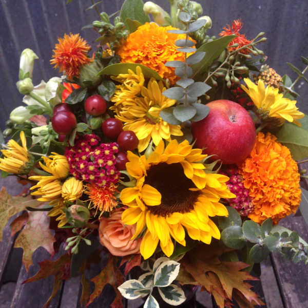 Autumn bouquet with sunflowers, marigolds, and a red apple