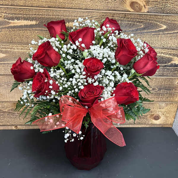 Red roses with white baby's breath in a dark vase and red bow