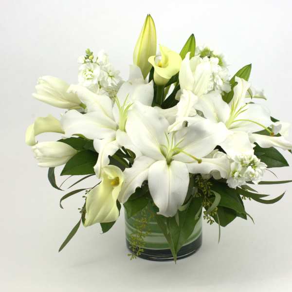 White lilies and calla lilies arranged in a glass vase