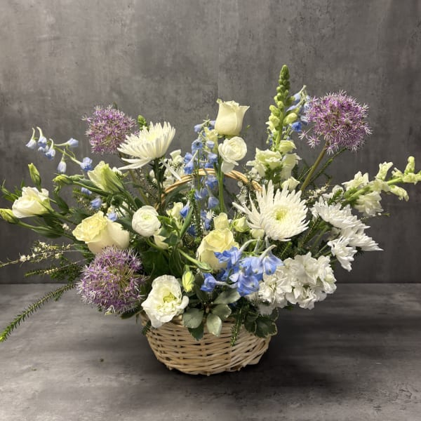 Basket arrangement of white and blue flowers with purple allium