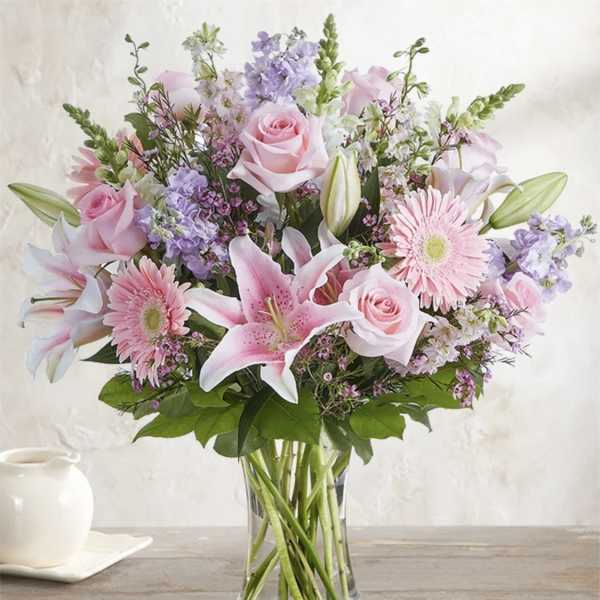 Pink roses, lilies, and gerbera daisies in a clear glass vase