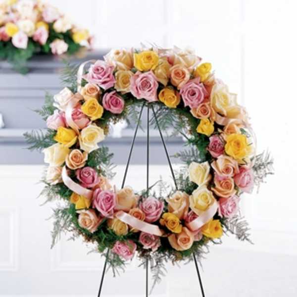 Circular wreath of pastel roses on a black stand