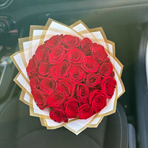 Bouquet of red roses wrapped in white and gold paper
