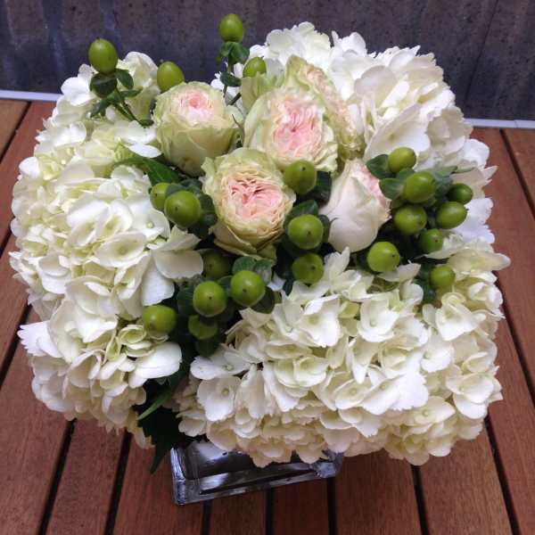 White hydrangea and pale pink roses in a square glass vase
